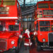 Santa standing between two red Routemaster buses at London Transport Museum