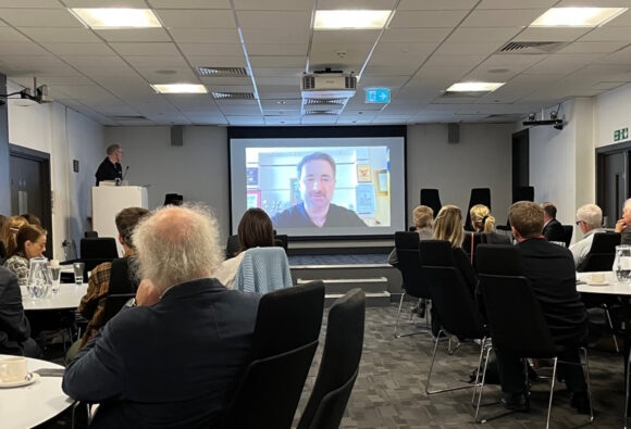 A caption of Igor Smelyanski of Ukrposta connected via a video call with delegates looking at his projection.