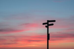 Photograph of a signpost in front of a sunset.
